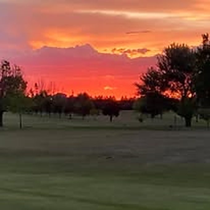 Vivid orange dusk sky above the course