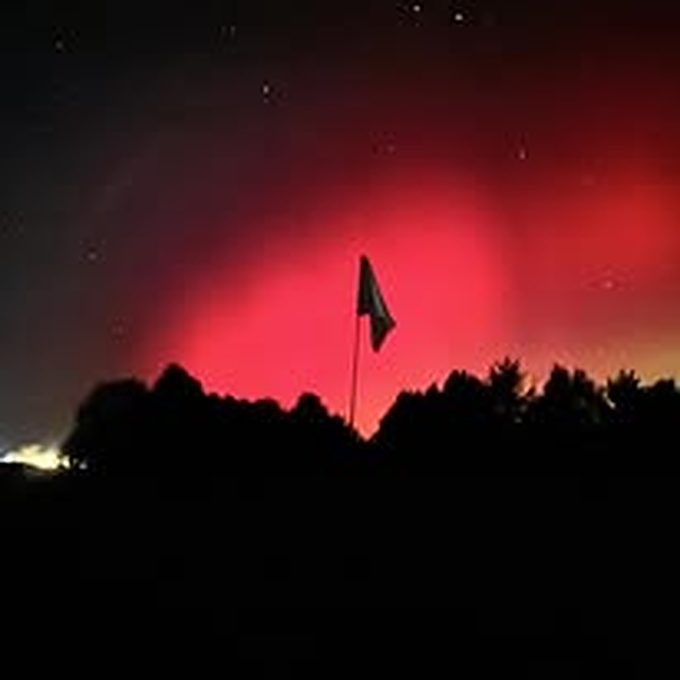 Deep red night sky behind a flagstick at F&H